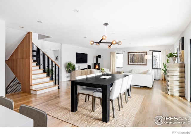 dining room with light hardwood / wood-style flooring, a chandelier, and a wood stove