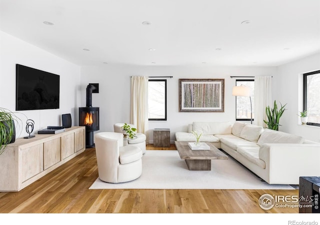 living room with a wealth of natural light, hardwood / wood-style floors, and a wood stove