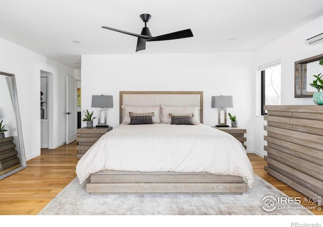 bedroom featuring hardwood / wood-style flooring, a wall unit AC, and ceiling fan