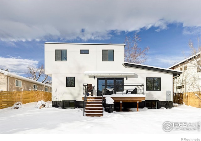 snow covered rear of property with a wooden deck