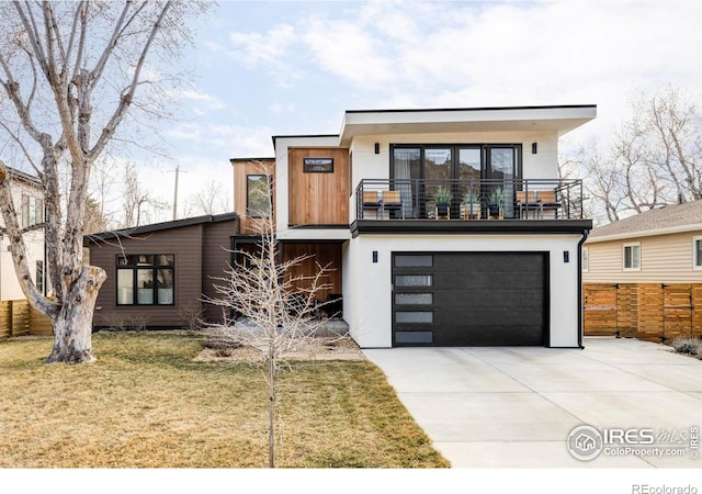 modern home featuring a front lawn, driveway, fence, an attached garage, and a balcony