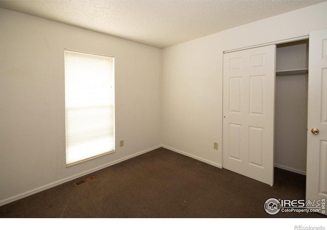 unfurnished bedroom featuring dark carpet and a closet