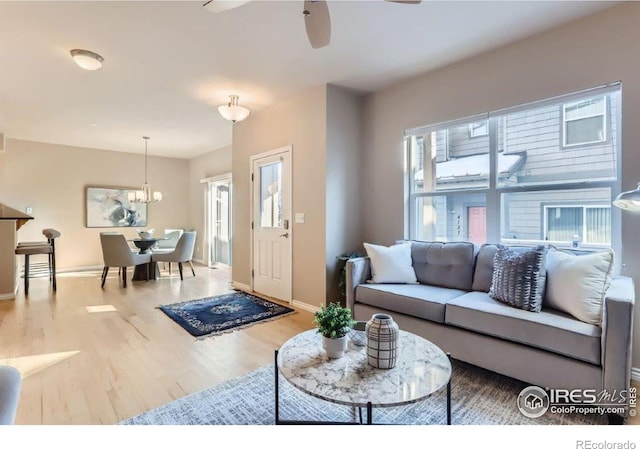 living room with ceiling fan with notable chandelier and wood-type flooring