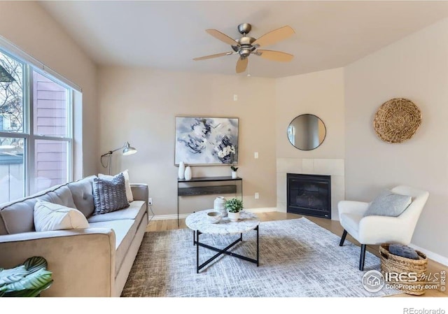 living room with a tiled fireplace, hardwood / wood-style floors, and ceiling fan