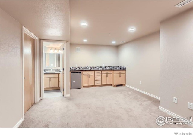 kitchen featuring light carpet, light brown cabinetry, fridge, and sink