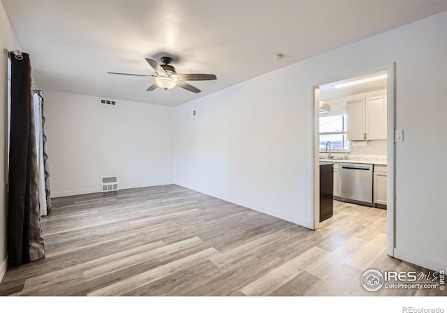 empty room with sink, ceiling fan, and light hardwood / wood-style flooring