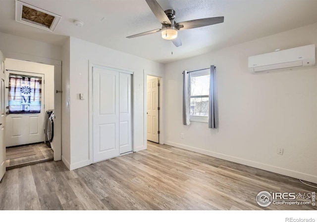 unfurnished bedroom featuring ceiling fan, a closet, light hardwood / wood-style floors, and a wall unit AC