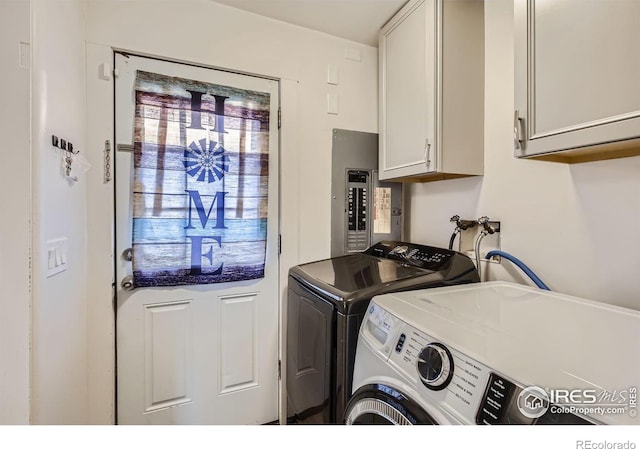 laundry area featuring washing machine and dryer, cabinets, and electric panel