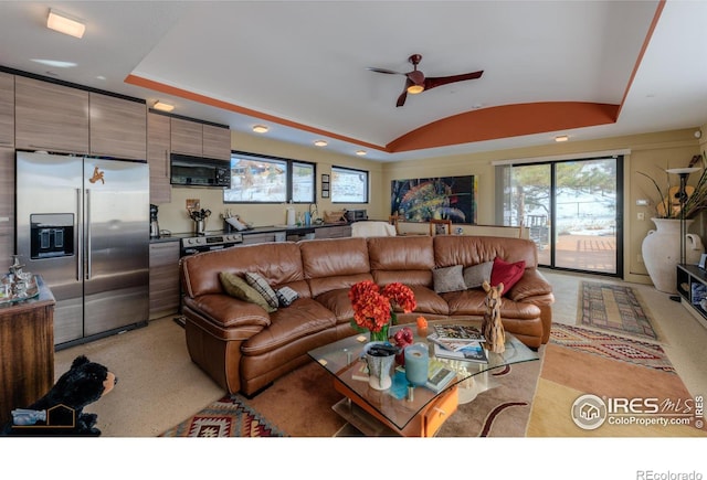 living room featuring vaulted ceiling, light colored carpet, and ceiling fan