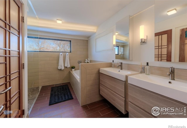 bathroom featuring vanity and a relaxing tiled tub