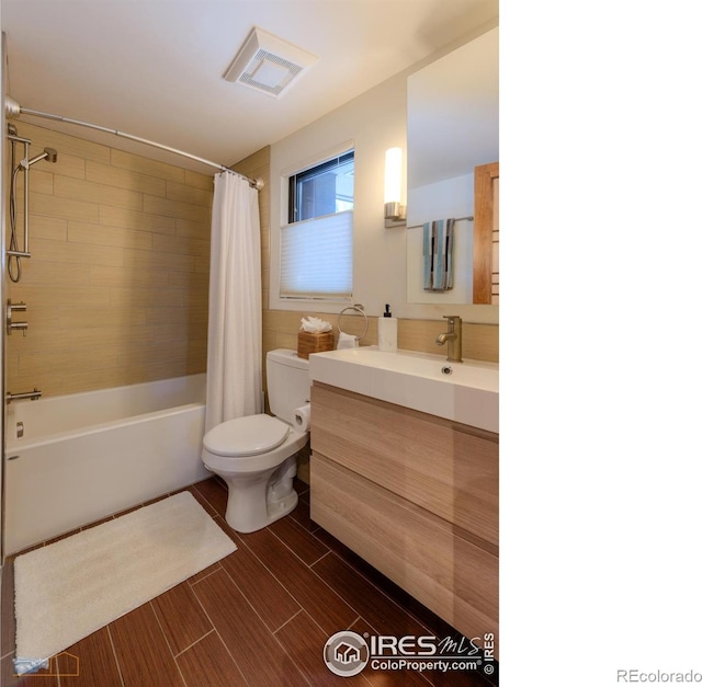 full bathroom with vanity, shower / bath combo with shower curtain, and toilet