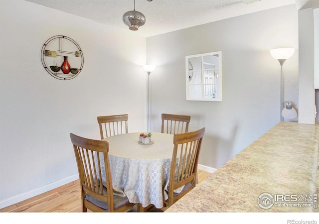 dining area with light hardwood / wood-style floors and a textured ceiling