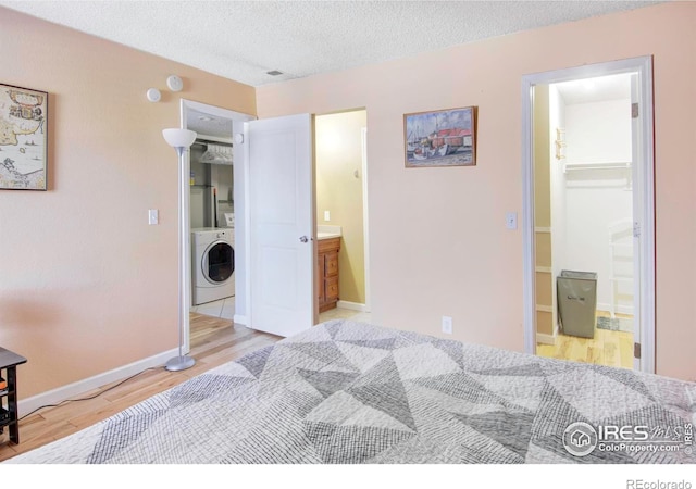 bedroom featuring connected bathroom, a walk in closet, a closet, washer / clothes dryer, and light hardwood / wood-style floors