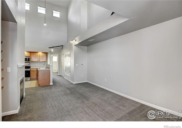 kitchen with sink, plenty of natural light, appliances with stainless steel finishes, and a high ceiling