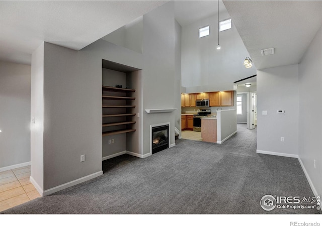 unfurnished living room featuring light colored carpet and a high ceiling