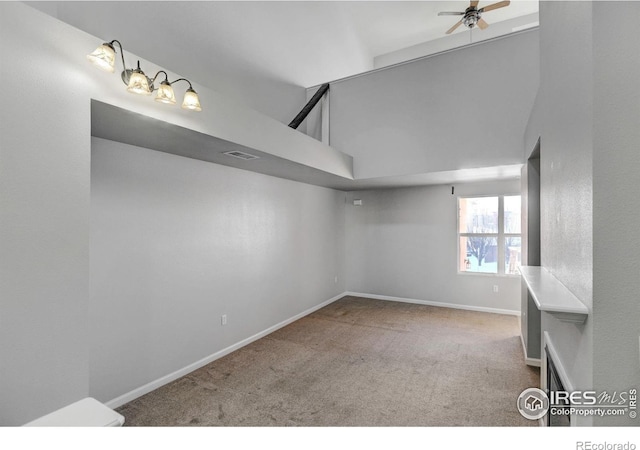 carpeted spare room with a towering ceiling and ceiling fan