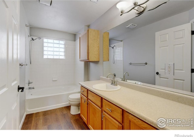 full bathroom with vanity, hardwood / wood-style flooring, tiled shower / bath combo, and toilet