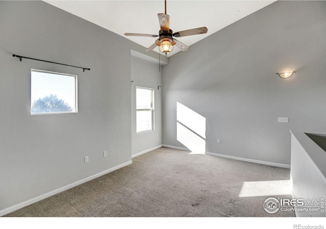 empty room with a wealth of natural light, light colored carpet, and ceiling fan