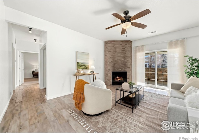 living room with ceiling fan, a fireplace, and light hardwood / wood-style flooring