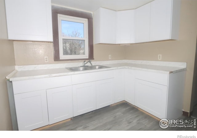 kitchen with white cabinetry, sink, and hardwood / wood-style floors