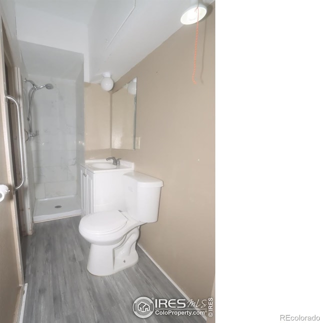 bathroom featuring vanity, hardwood / wood-style floors, toilet, and tiled shower