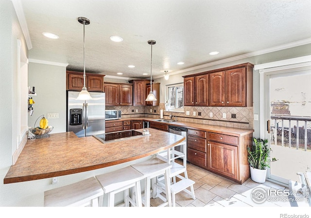 kitchen featuring sink, a breakfast bar area, kitchen peninsula, pendant lighting, and stainless steel appliances