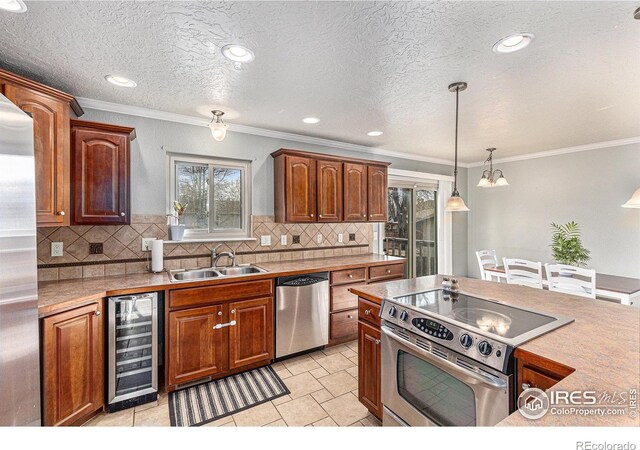 kitchen with sink, light tile patterned floors, hanging light fixtures, stainless steel appliances, and beverage cooler