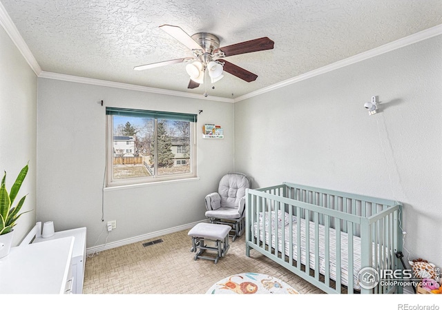 bedroom with a nursery area, ceiling fan, crown molding, and a textured ceiling