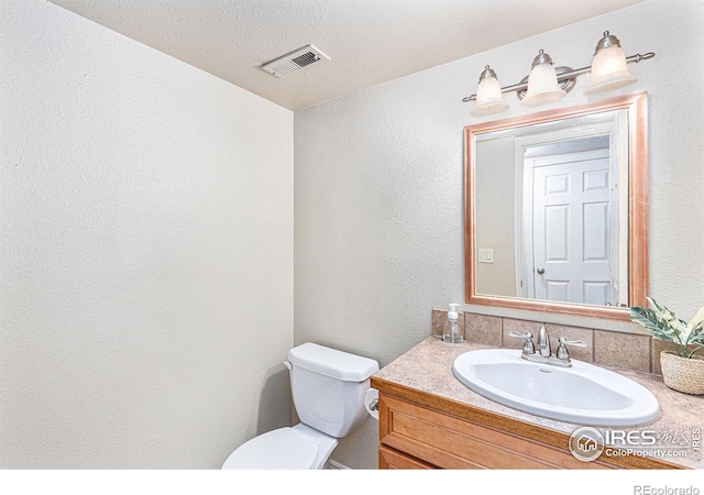 bathroom with vanity, a textured ceiling, and toilet