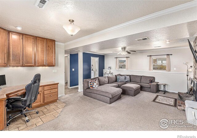 carpeted office space with ceiling fan, crown molding, built in desk, and a textured ceiling