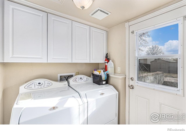 clothes washing area featuring cabinets and washing machine and clothes dryer