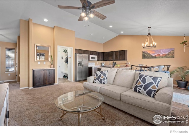 carpeted living room featuring ceiling fan with notable chandelier and high vaulted ceiling