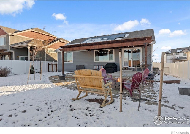 snow covered rear of property featuring solar panels