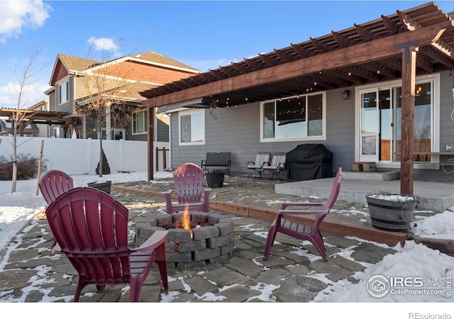 snow covered patio featuring area for grilling, an outdoor fire pit, and a pergola