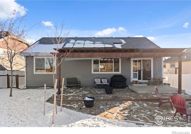 snow covered property with a patio and solar panels