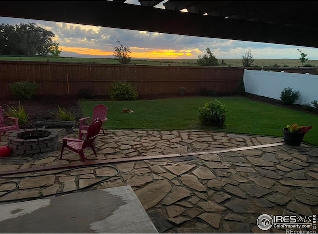 patio terrace at dusk featuring a yard and a fire pit