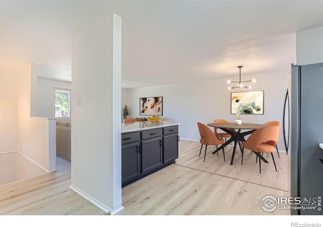 kitchen featuring light countertops, light wood-style flooring, freestanding refrigerator, and pendant lighting