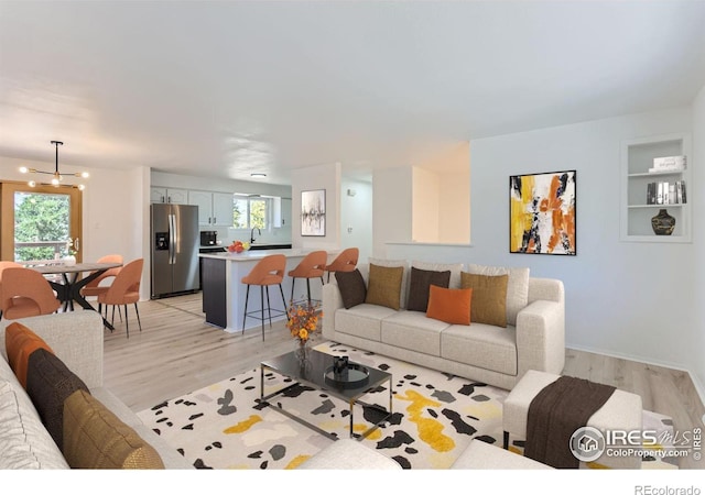 living area with a chandelier, plenty of natural light, and light wood-style flooring