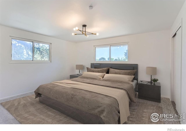 bedroom with a closet, baseboards, a notable chandelier, and carpet flooring