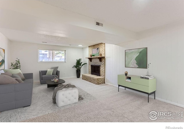 living room with a brick fireplace, baseboards, visible vents, and light colored carpet