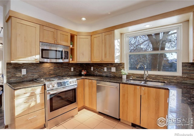 kitchen with appliances with stainless steel finishes, sink, dark stone countertops, and backsplash