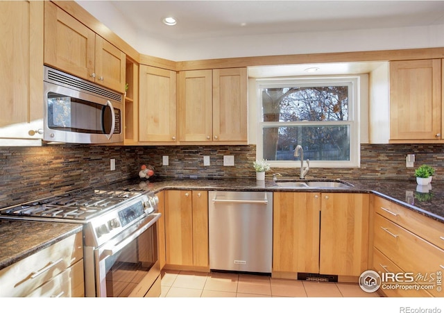 kitchen with sink, backsplash, dark stone counters, and appliances with stainless steel finishes