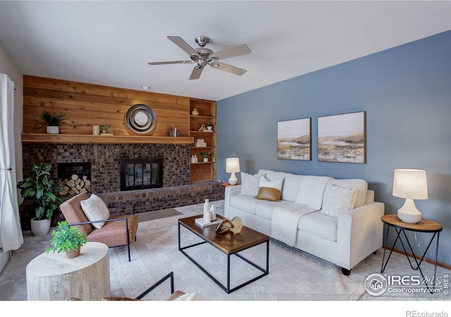 carpeted living room with ceiling fan, wooden walls, a fireplace, and built in shelves