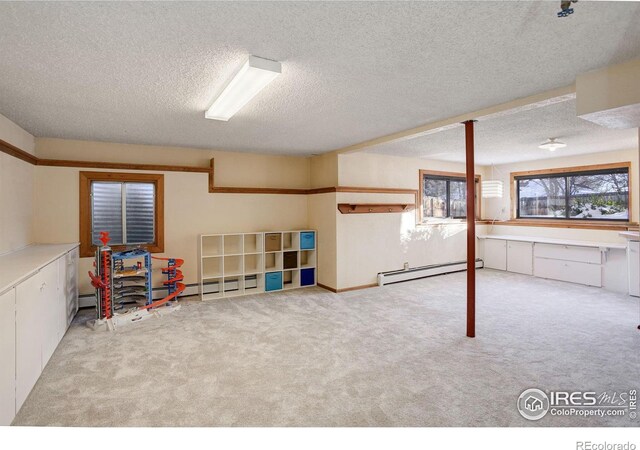 basement with a baseboard heating unit, light carpet, and a textured ceiling