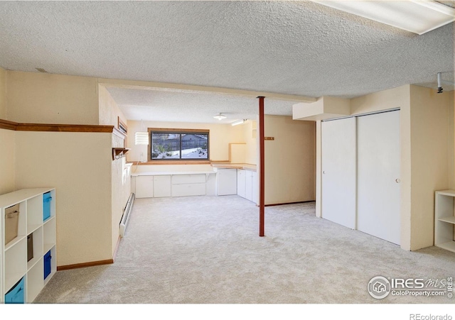 interior space with light carpet, a textured ceiling, and baseboard heating