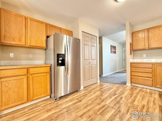 kitchen with light hardwood / wood-style flooring, a textured ceiling, and stainless steel fridge with ice dispenser