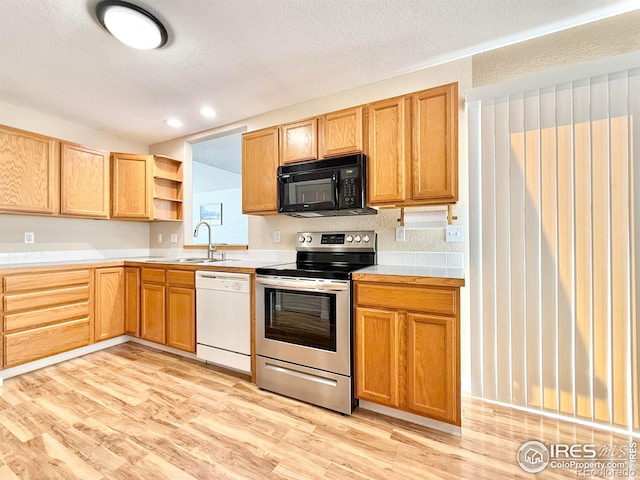 kitchen with sink, light hardwood / wood-style floors, white dishwasher, a textured ceiling, and electric stove