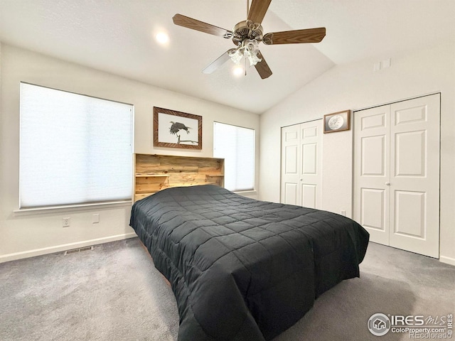 carpeted bedroom featuring multiple closets, ceiling fan, and vaulted ceiling