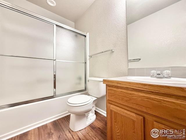 full bathroom featuring vanity, hardwood / wood-style floors, enclosed tub / shower combo, and toilet