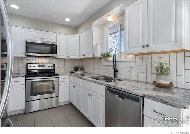 kitchen with tasteful backsplash, sink, white cabinets, light tile patterned floors, and stainless steel appliances